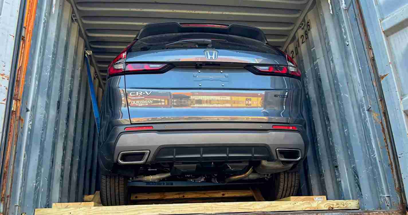 Blue Honda CR-V loaded upright in a shipping container, rear view, on wooden supports.
