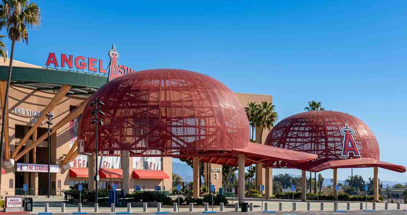 Exterior view of Angel Stadium with distinctive red geodesic domes and clear blue sky, signage visible.