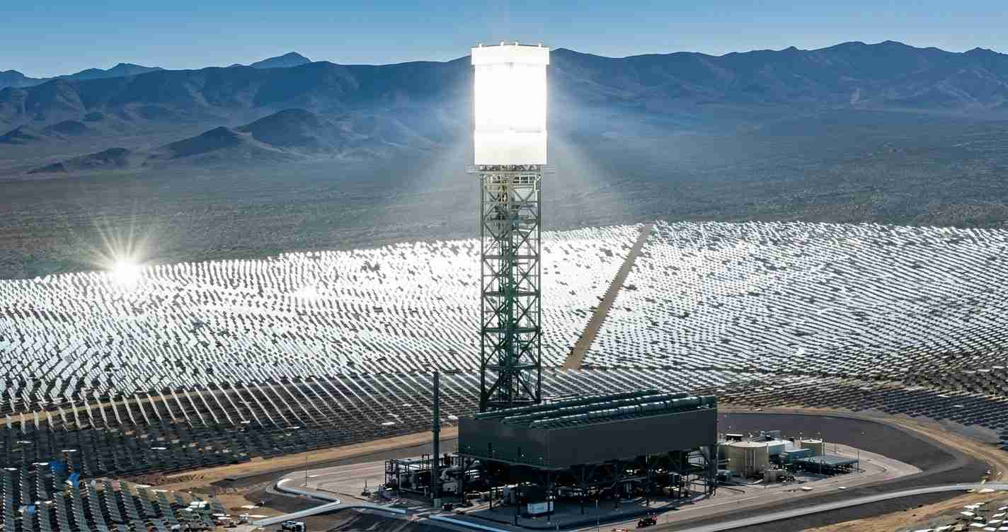 Central receiver tower at a solar thermal power plant, surrounded by mirrors (heliostats) in a desert valley.