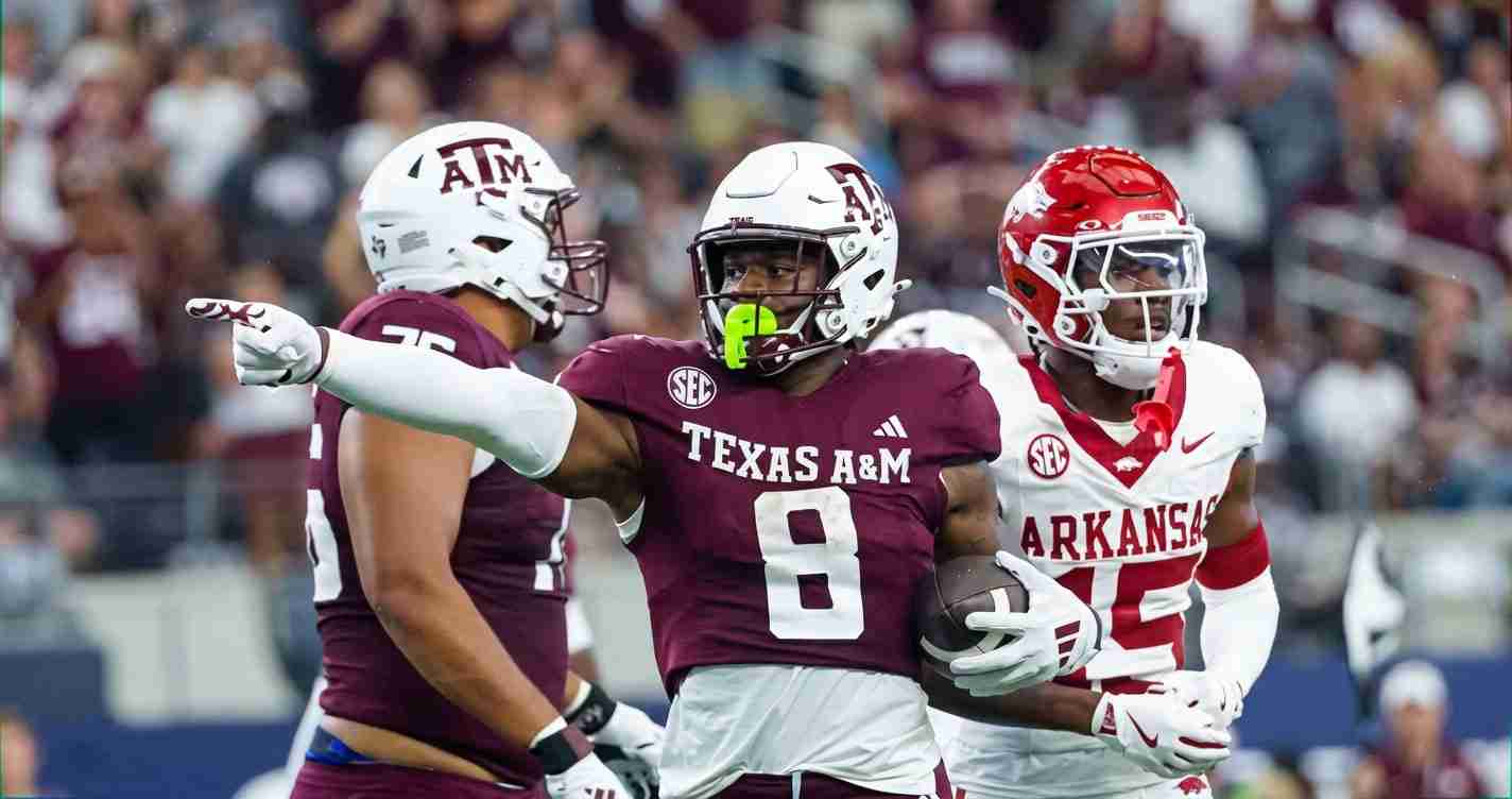 Texas A&M running back #8 carries the ball while an Arkansas defender closes in during a college football game.