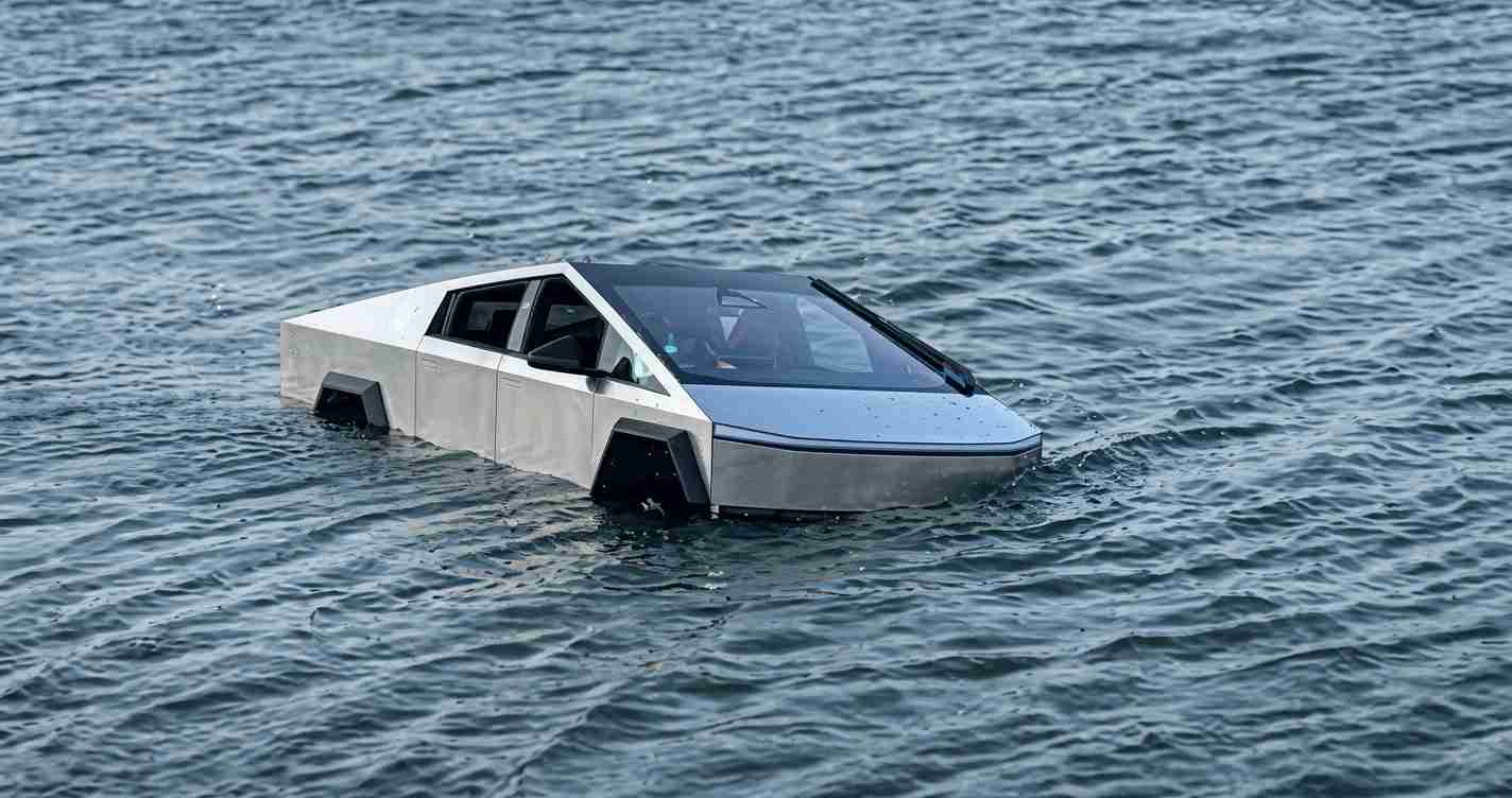 Silver, angular car floating in the sea, partially submerged with its windshield wipers visible.