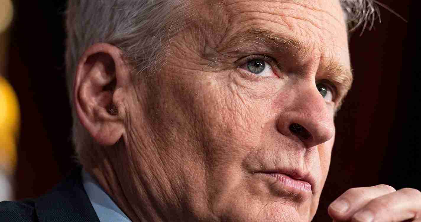 Close-up of an older man’s face in a thoughtful, pensive pose with wrinkles visible on the skin and gray hair edge showing at the temple.