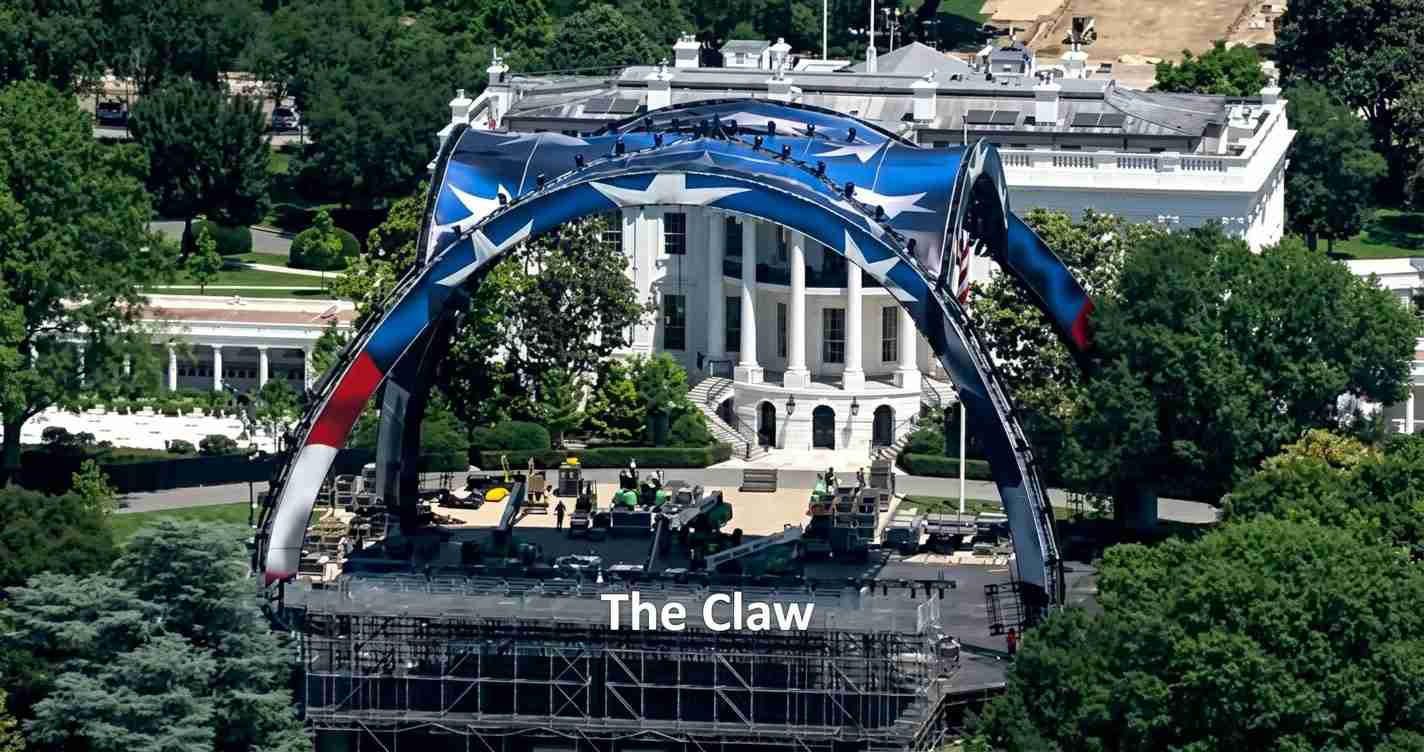 Large outdoor stage rig in front of a white neoclassical building, with a curved blue-red-white arch overhead and the words “The Claw.”