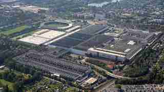 Aerial view of a large stadium and adjacent sports facilities surrounded by parking lots and a city neighborhood.