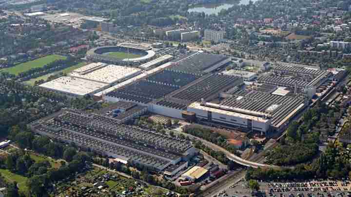 Aerial view of a large stadium and adjacent sports facilities surrounded by parking lots and a city neighborhood.