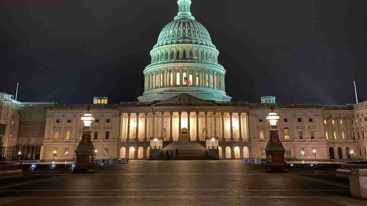 Night view of the U.S. Capitol illuminated, with grand steps and neoclassical façade in the foreground.