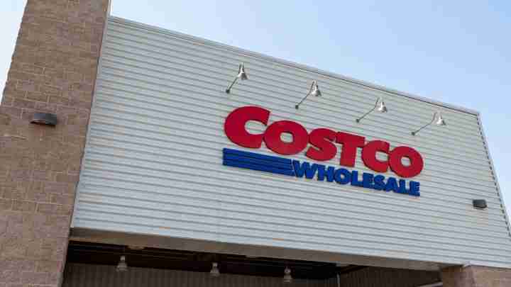 Costco Wholesale storefront sign on a corrugated metal wall with red 'Costco' and blue 'Wholesale' lettering