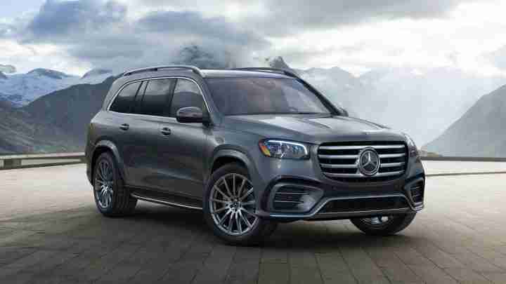 Silver Mercedes-Benz SUV parked on a tiled surface with snow-capped mountains in the background at a scenic overlook.