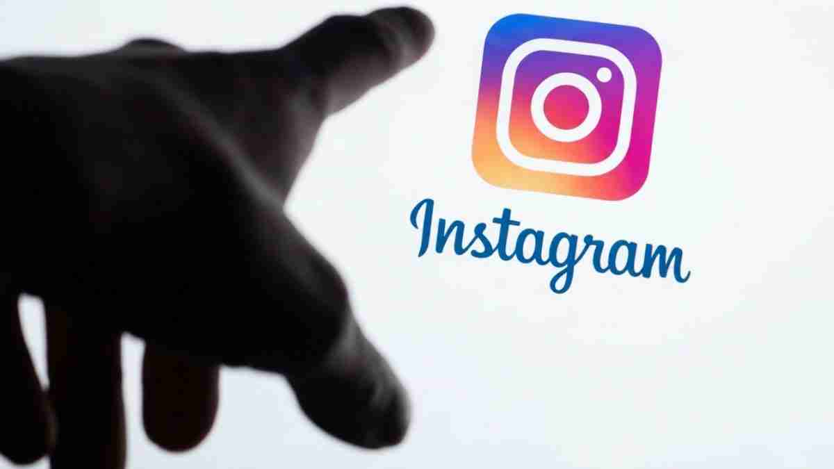 A dark silhouette of a hand reaching toward the colorful Instagram logo on a pale background.