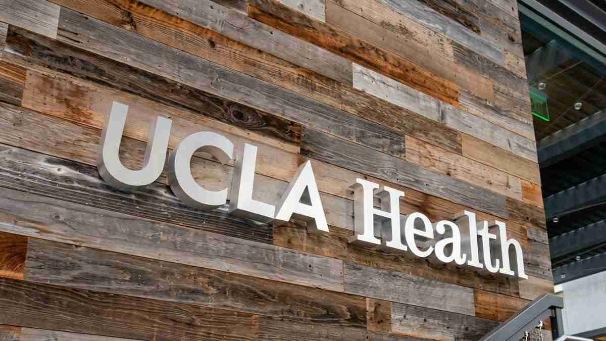 UCLA Health sign mounted on a wood-paneled wall outside a building.