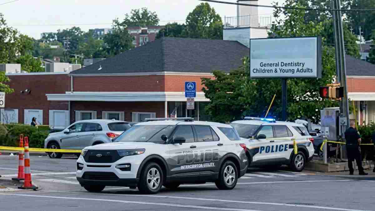 Police cars block a street outside a dental clinic, with yellow caution tape across the road and a sign for General Dentistry for Children & Young Adults nearby.