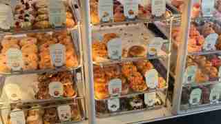 Display case full of assorted donuts and pastries with labeled flavor tags.