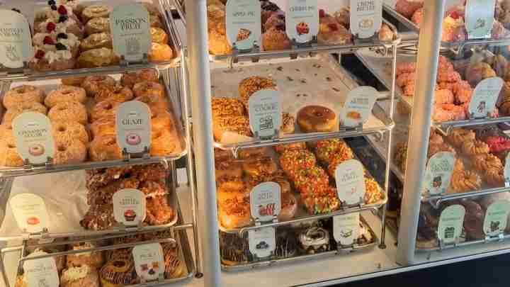 Display case full of assorted donuts and pastries with labeled flavor tags.