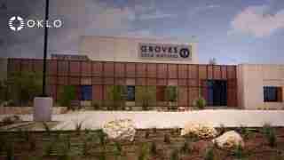 Exterior view of the Groves OKLO Isotopes building with the OKLO logo in the foreground, desert landscaping in front.